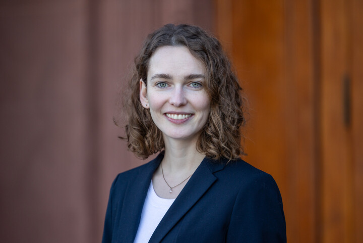 Carolin Unterricker has brown, shoulder-length hair and wears a blue blazer. She smiles at the camera.